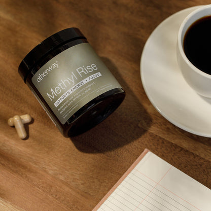 Supplement labeled 'Methyl Rise' on a wooden surface with a cup of coffee and a notebook.